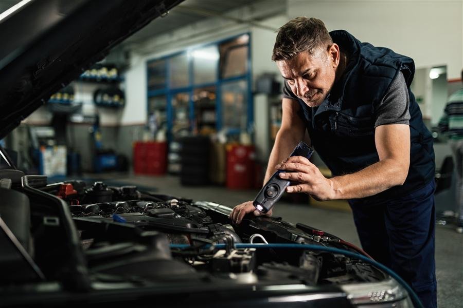 Mecânico examinando motor com lanterna